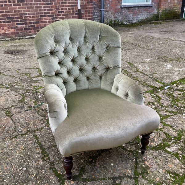 Antique Victorian button back armchair with green upholstery.