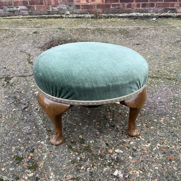 Antique green button footstool with turned wooden legs.