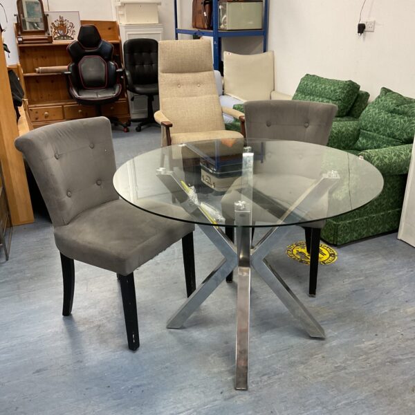 Round glass dining table with two chairs in a dining room.