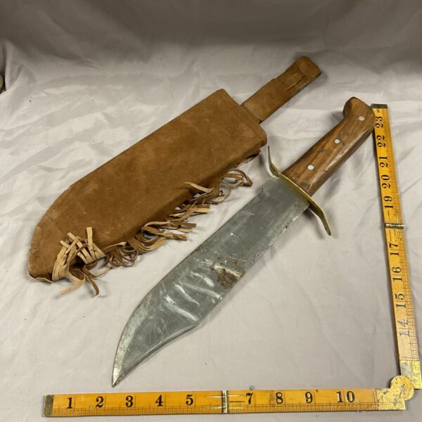 Vintage Bowie knife with leather sheath, showing blade and handle.