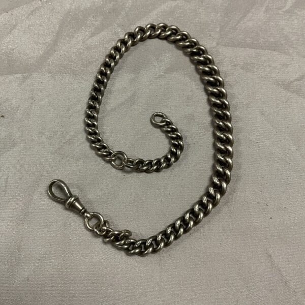 Close-up of antique silver watch chain with stamped links.