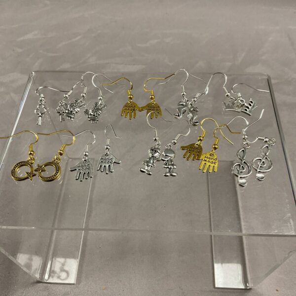 Close-up of ten pairs of 925 silver earrings on a dark surface.