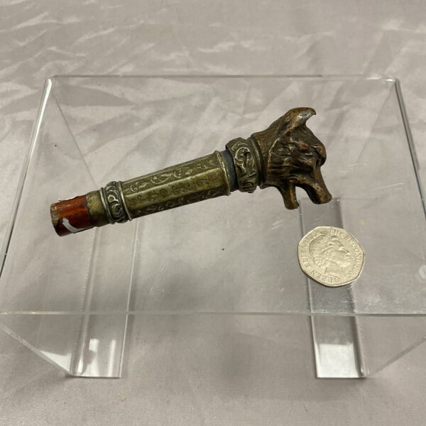 Antique bronze dog head cane top displayed on a clear stand.