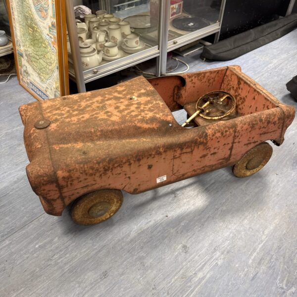 Rusty antique pedal car, vintage toy for restoration.
