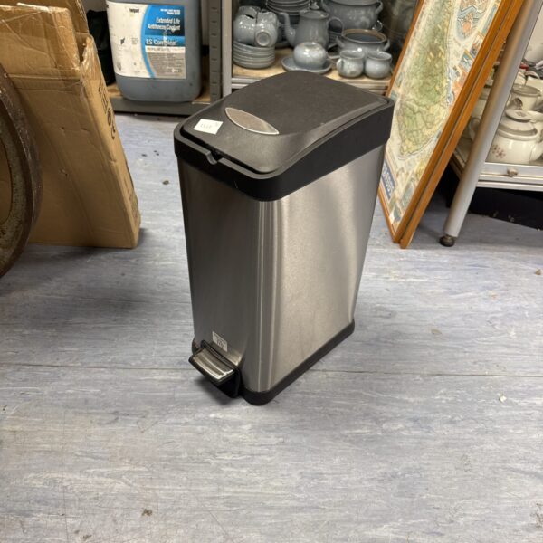 Silver stainless steel pedal bin in a storage area.