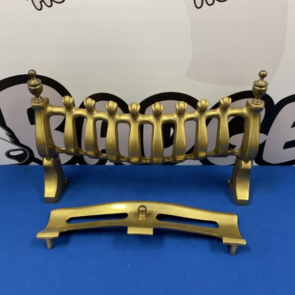 Antique brass fireplace fender with decorative feet.