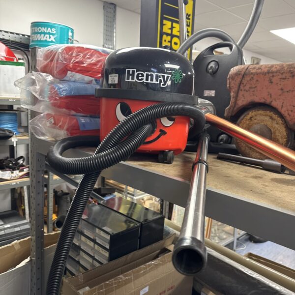 Red Numatic Henry hoover with extension pole for domestic cleaning.