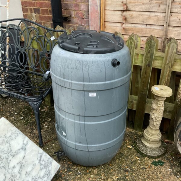 Grey plastic water butt in a garden setting for rainwater collection.