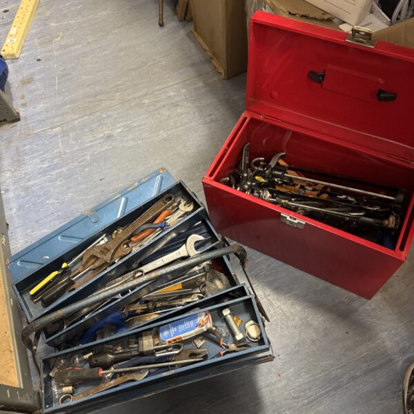 Vintage metal toolboxes filled with a variety of hand tools.