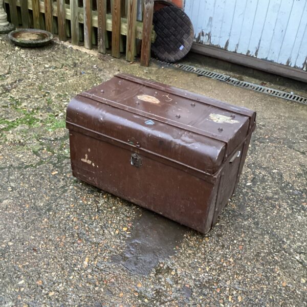 Exterior view of a vintage metal trunk with signs of age.