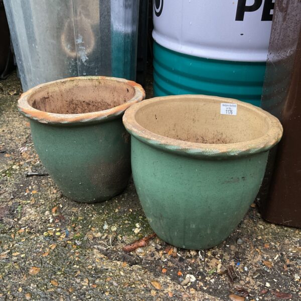 Pair of green glazed terracotta garden pots in a garden setting.