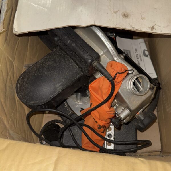 Side view of a used Challenge 1200w mitre saw in a cardboard box.