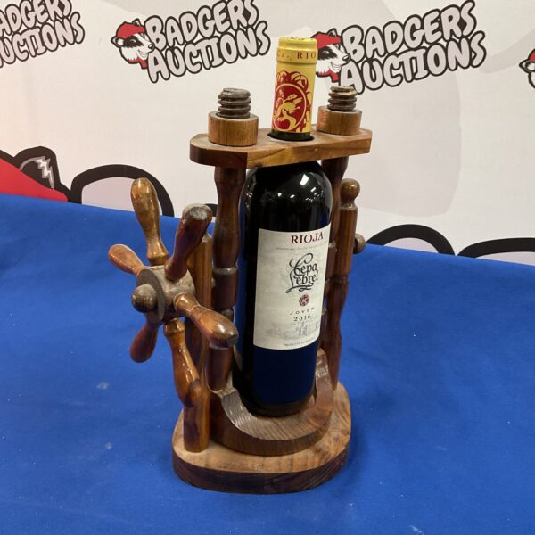 Wooden ships wheel wine pourer displaying a bottle of Rioja.