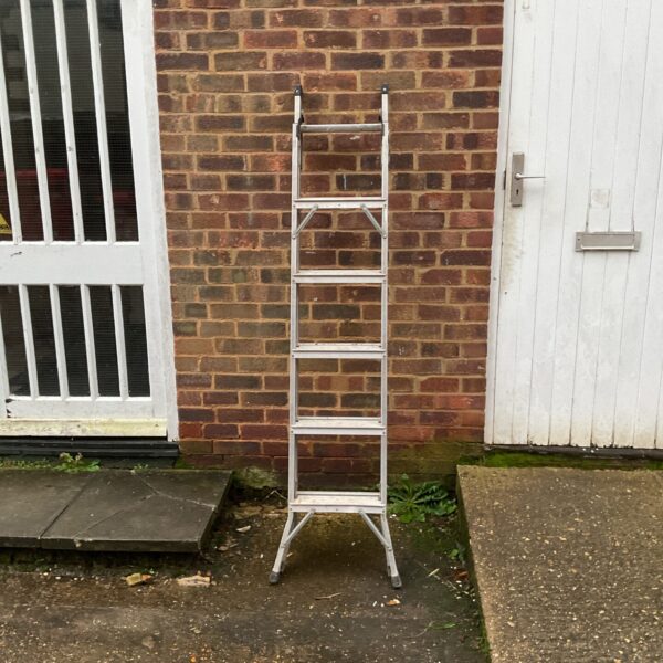 Aluminium extending ladder leaning against a brick wall.