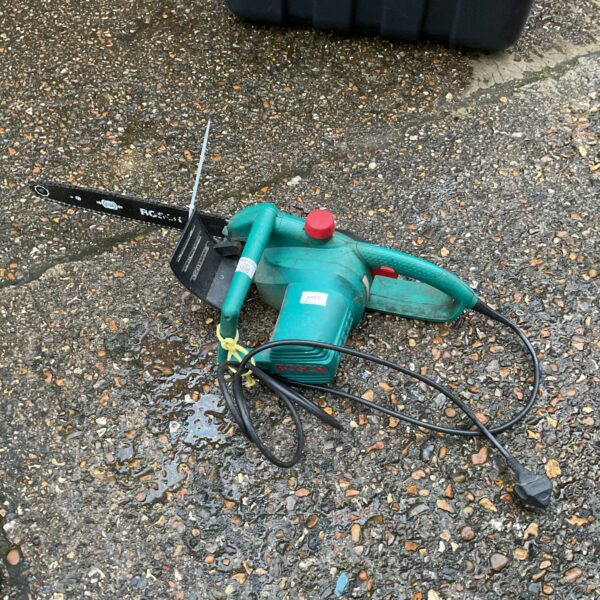 Used Bosch electric chainsaw with spare chain for garden maintenance.