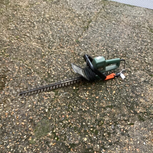 Used Black and Decker electric hedge trimmer on a gravel surface.