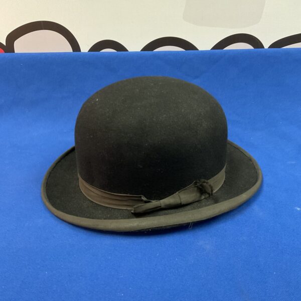 Classic vintage black bowler hat on blue background.