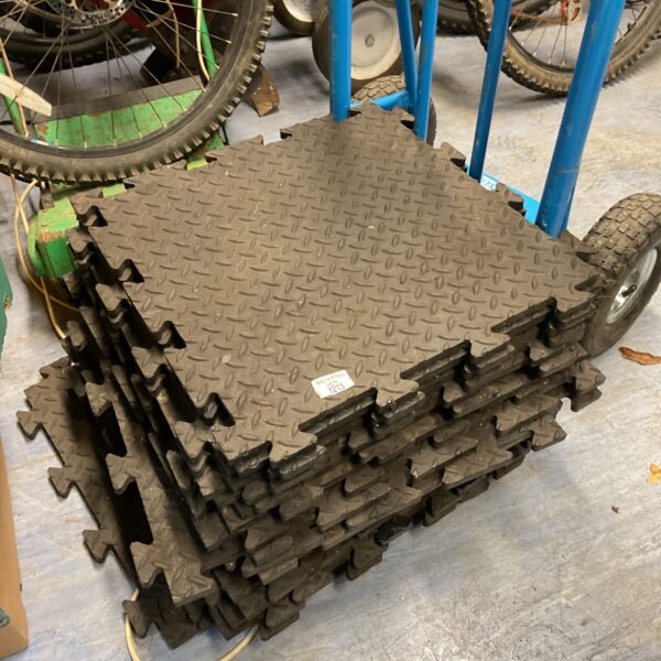 Stack of interlocking rubber floor matting tiles for workshop or gym.
