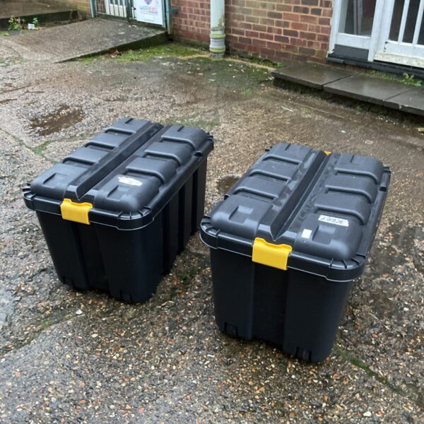Two large wheeled storage boxes on a paved surface.