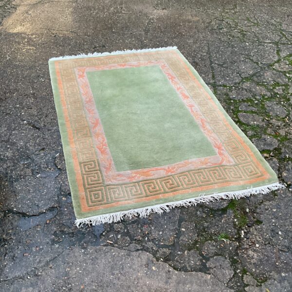 Vintage green and orange patterned rug with geometric design.