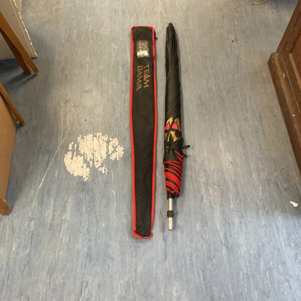 Red and black Team Daiwa umbrella for fishing and sports.