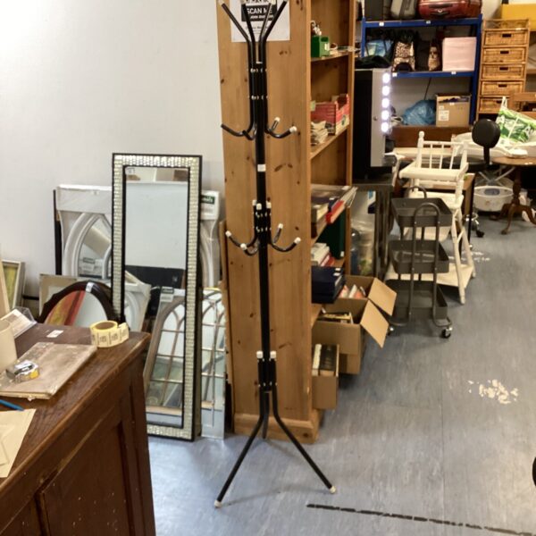 Vintage wooden coat rack with curved hooks in a hallway.