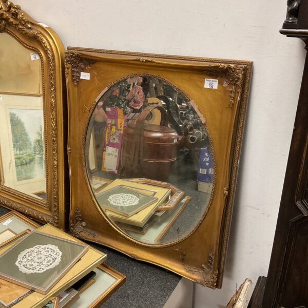 Ornate antique gilt framed mirror with oval reflection.