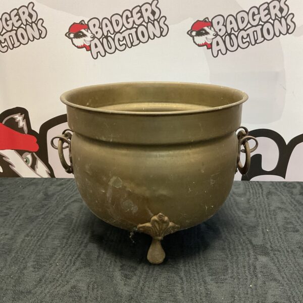 Vintage brass cauldron with claw feet, antique hearth decor.