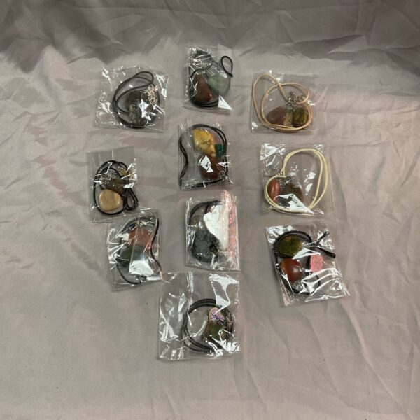 Assorted crystal necklaces in plastic bags, colourful gemstone pendants.