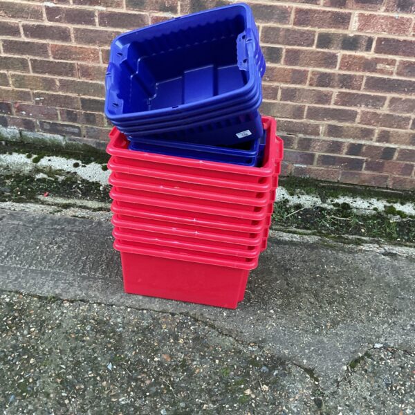 Lot of fourteen empty plastic storage boxes stacked together.