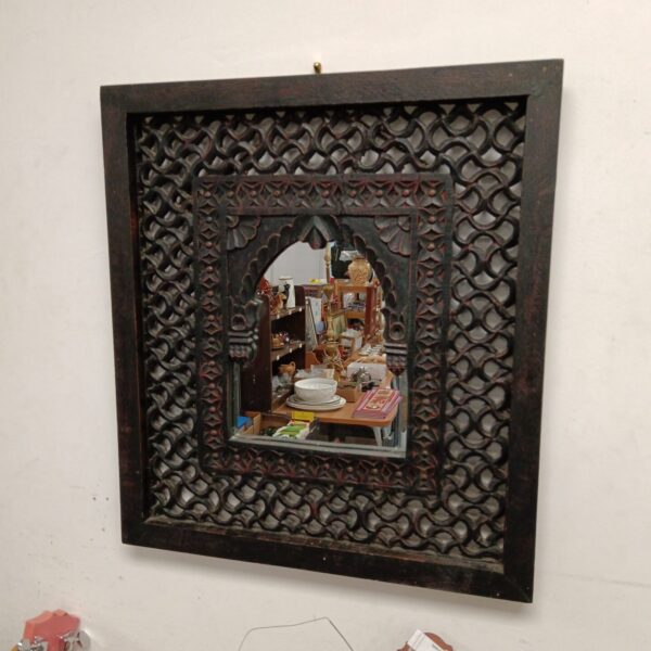 Ornate Indian carved mirror with intricate wooden frame.
