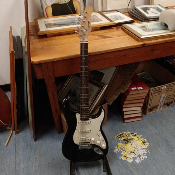 Black Stagg electric guitar displayed on a stand.