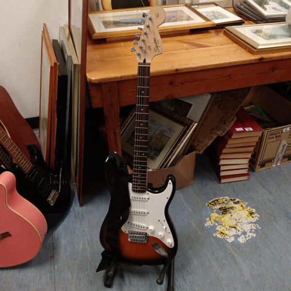 Fender Squire Strat electric guitar displayed on a stand.