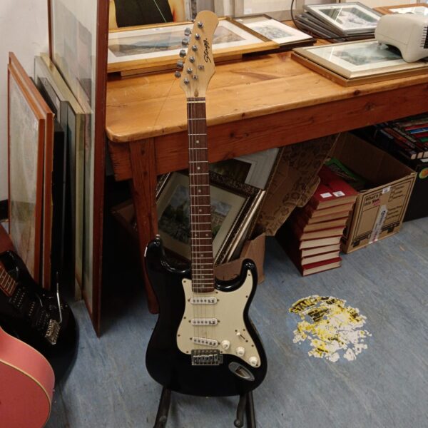 Black Stagg electric guitar displayed on a stand.