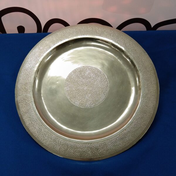 Silver hand hammered charger plate with textured surface.