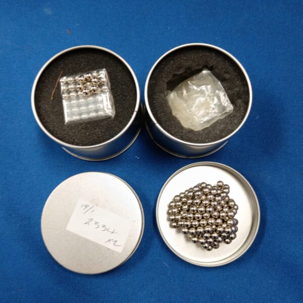 Two sets of magnetic balls in metal tins.