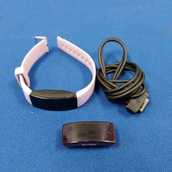Pink Fitbit watch with charging cable for fitness tracking.