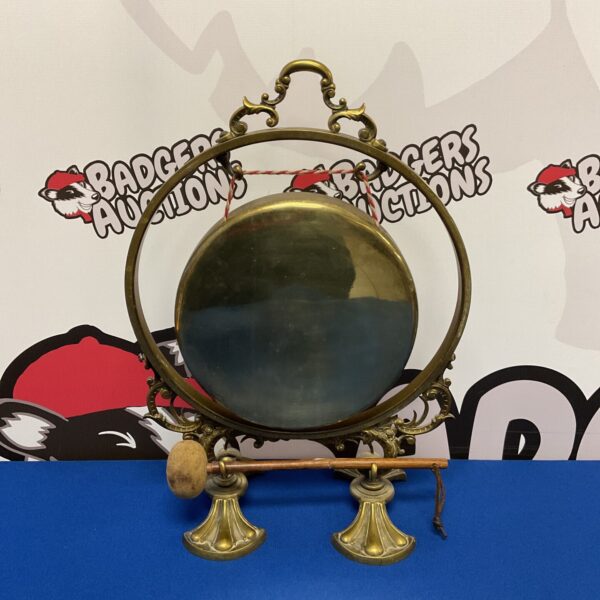 Vintage brass dinner gong on a table, a classic dining accessory.
