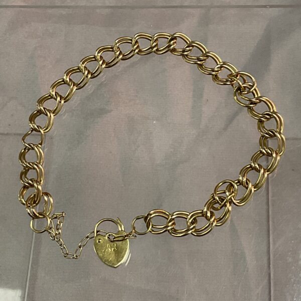 Vintage 9ct gold padlock bracelet on a grey surface.