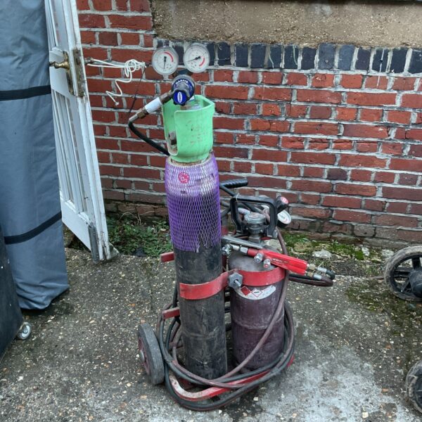 Vintage acetylene torch set with gas bottles on wheels.