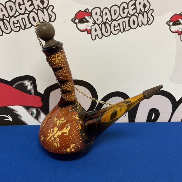 Vintage Spanish wine decanter in amber glass with intricate detailing.