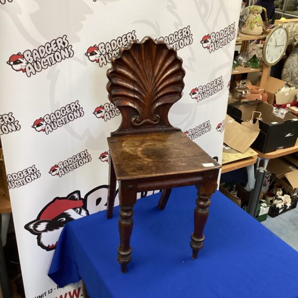 Antique hall chair with a sculpted scalloped back, vintage hardwood seating.