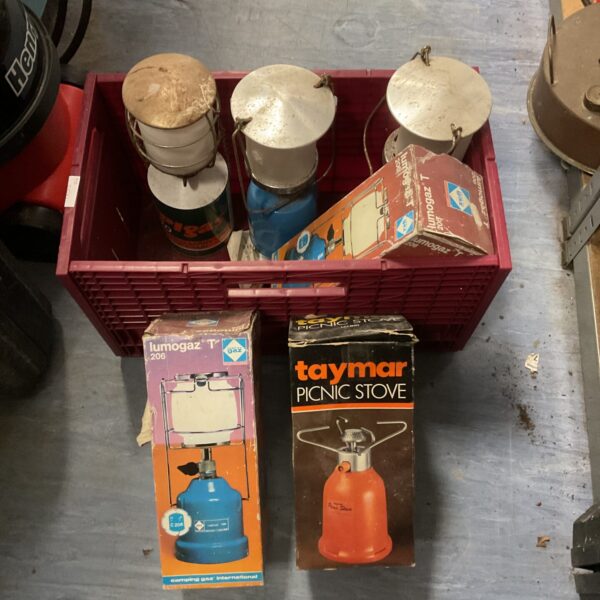 Vintage camping gas stoves and lanterns in a box.