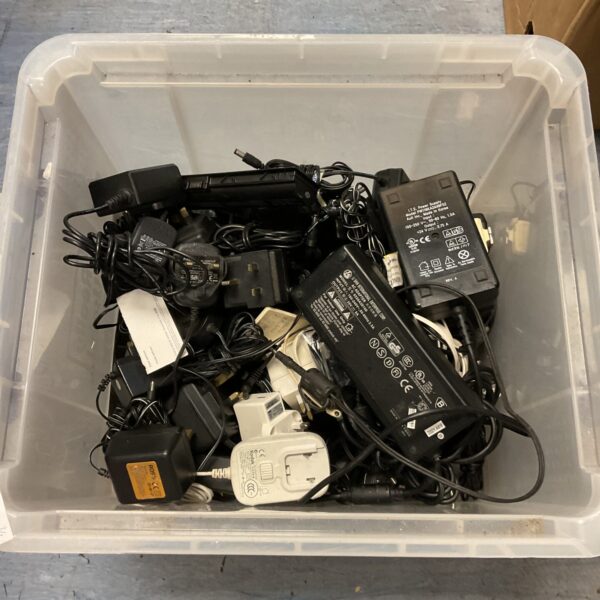 Mixed lot of vintage and modern power supplies for electronics.