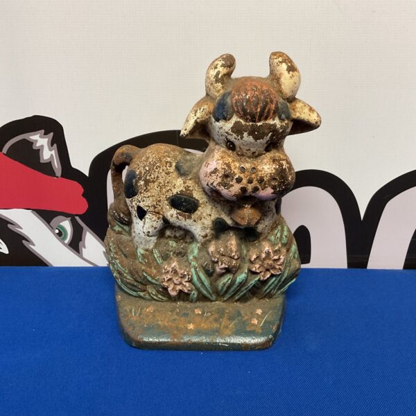 Antique cast iron cow doorstop with floral details, vintage farmhouse decor.