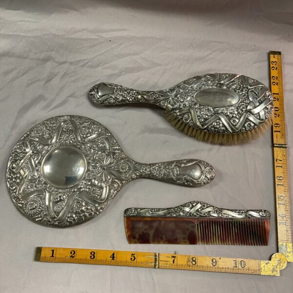 Antique silver dressing table set with mirror and brushes.