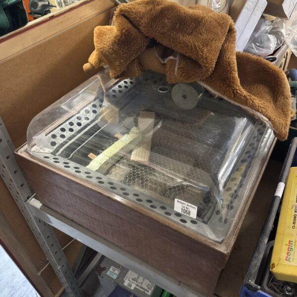 Vintage egg incubator with wire mesh tray for hatching eggs.