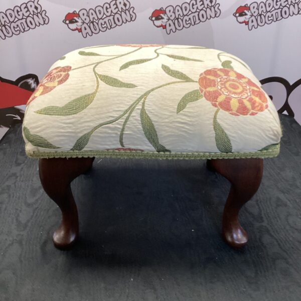 Vintage floral footstool with turned wooden legs.
