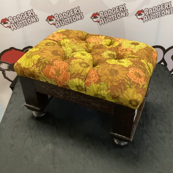 Vintage floral footstool with turned wooden legs.