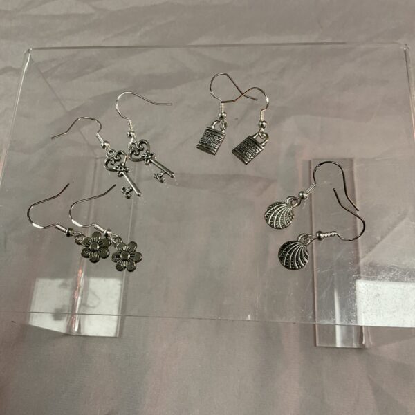 Close-up of four pairs of 925 silver earrings with varied designs.